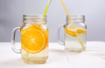 Water with orange and lemon in glass jars