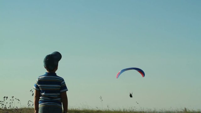 The child watches the landing of the paraglider