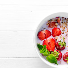 bowl of granola with strawberries, textspace left, topview