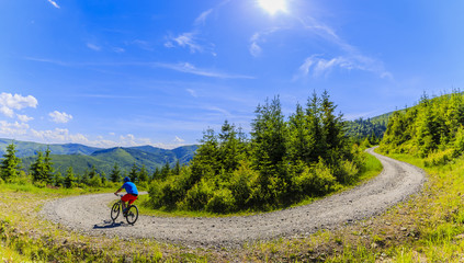 Mountain biker riding on bike in summer mountains forest landscape. Man cycling MTB outdoor sport...