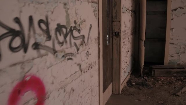FPV, CLOSE UP: Exploring decaying residential part of abandoned City Methodist Church in Gary, Indiana, USA. Walking past scary crumbling halls and ruined rooms with paint peeling from the walls