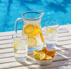 A jar and two glasses of refreshing ice water for hydration in hot weather.