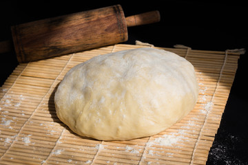 Dough Flour Wooden Rolling Pin on Black Background.