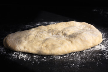 Pizza Dough Baking on Dark Black Background. Baking bread, pizza, pasta. Recipe from chef cooks pizza. Italian home cooking.