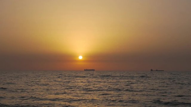 Sunset over the Mediterranean sea, transport vessels on background, Ashdod, Israel.