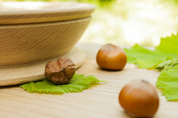 hazelnuts in a wooden bowl with green leaves on wooden background,the cleaned nut