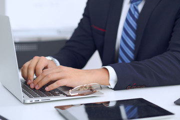 Young man working with laptop computer, man's hands on notebook, business person at workplace