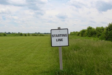 The starting line sign with the grass field and sky in the background.
