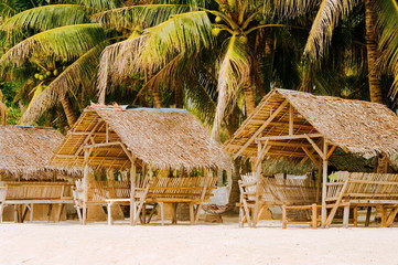 Fototapeta na wymiar Summer sunshades and bamboo armchair on the tropical white sand beach,