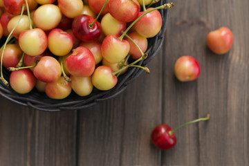 Ripe red yellow cherries in basket on brown background