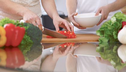 Close-up of four human hands are cooking in a kitchen. Friends having fun while preparing fresh...
