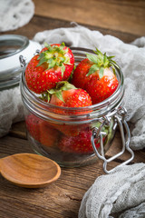 Strawberry in jar on wooden background.