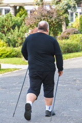 Big man Nordic Walking in beautiful public park