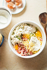 Courgette cake (frittata) ingredients mixed in white bowl - eggs, flour, grated courgette, bacon, feta, mascarpone and cheddar