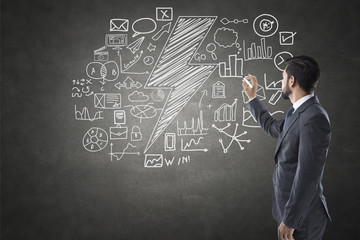 Businessman drawing icons on blackboard