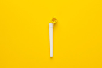 paper and plastic party horn on the yellow background