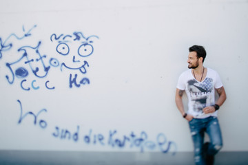 Mann lehnt an blau weißer Grafiti Wand