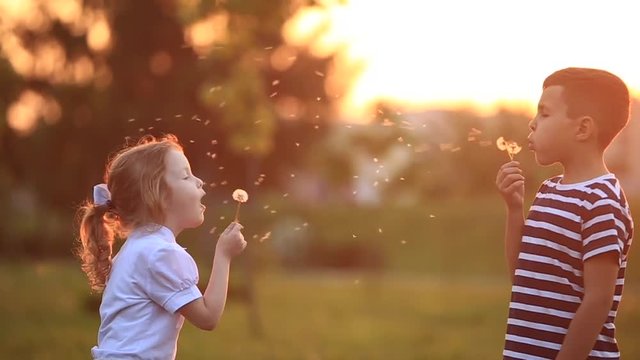 Little boy and little girl are sitting on a bench in the park. Walk and run around the park. Sunset