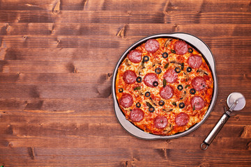 Baked pizza ready to be sliced in the baking pan