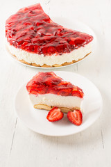Delicious homemade cake with strawberries on white wooden table.