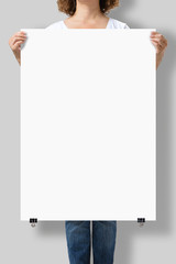 Woman holding a blank A1 poster mockup isolated on a gray background. - obrazy, fototapety, plakaty