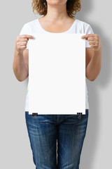 Woman holding a blank A3 poster mockup isolated on a gray background.