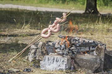 In summer, sausages are fried on sticks in the woods on sticks.