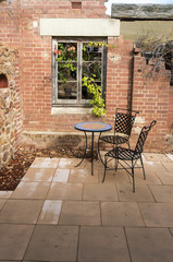 A small intimate courtyard with a single table and two chairs. Copyspace.