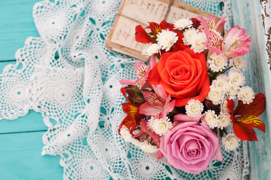 Bouquet roses and old letters on wooden desk in a vintage style.
