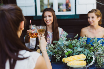 Frauen am Tisch prosten sich zu beim Grillabend
