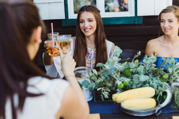 Frauen am Tisch prosten sich zu beim Grillabend