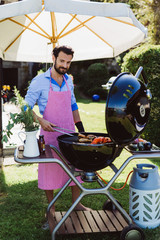 Man chef at barbecue with girls at table behind
