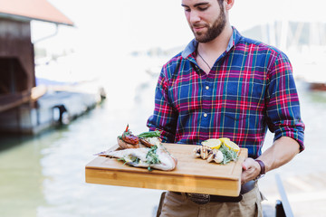 Man holding wooden plate with fresh fish