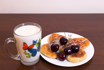 Curd fritters with milk
Syrniki - cheese pancakes, curd fritters - traditional Russian and Ukrainian snack, on white plate, served with cherries and a glass of milk