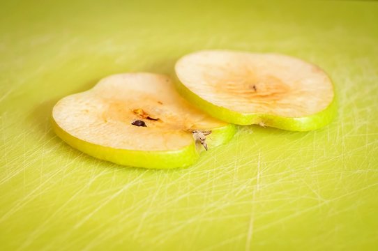 Two thin green apple slices on a cutting board turned brown due to the oxidation process close up stock image.