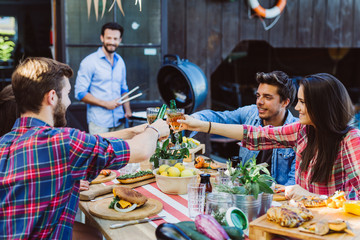 Man at smoker and friends at table cheering