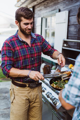 Man at grill barbecue with sausage smiling