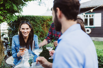 Friends chatting at garden party with glasses and beer bottles