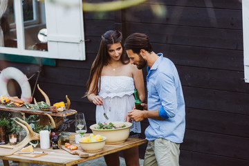 Couple at barbecue party cooking salad