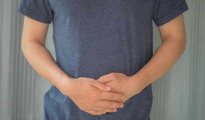 Man with both palm around waistline to show pain and injury on belly area. Medical health care concept.