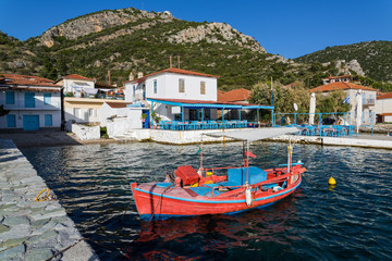 Fototapeta na wymiar Red fishing boat and white houses at the village of Agia Kyriaki in Thessaly, Greece