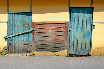 Yellow plastered facade with blue wooden doors. Yellow Wall Background