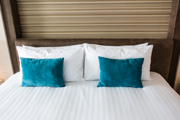 Beautiful king size bed with blue and white pillows with brown background