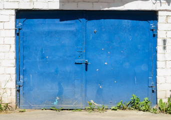Garage facade with blue metal gates. Old garage door background