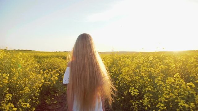 Pretty young girl walks and turns around with waving hair in the rape field