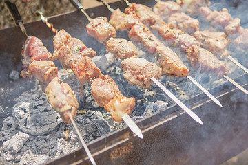 Pork or lamb meat pieces being fried on a charcoal grill