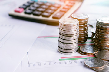 pile of coins and calculator on business and financial graph report background