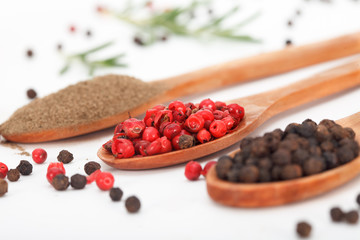 Black and red peppers in wooden spoons. Healthy food ingridients.