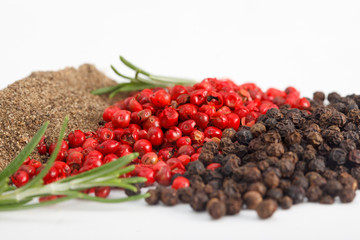 Heaps of black and red pepper with rosemary. Grinded pepper and peppercorns.
