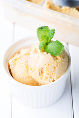 Homemade ice cream with salted caramel in a bowl on a white wooden background, soft focus, vertical
